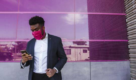man wearing pink mask using mobile phone