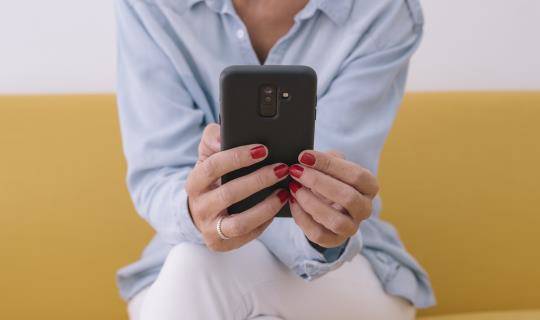 woman using smartphone on yellow couch