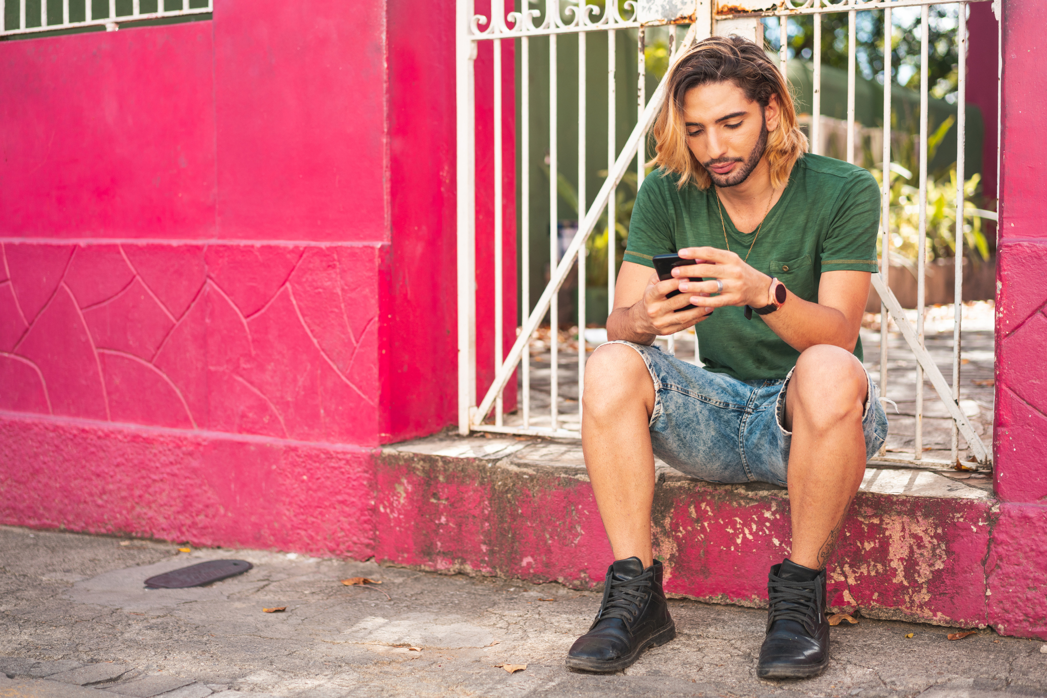 young man on smartphone pink wall