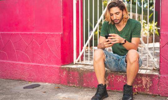young man on smartphone pink wall